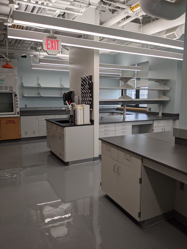 New laboratory with grey shiny floor, white cabinets, and light blue walls.